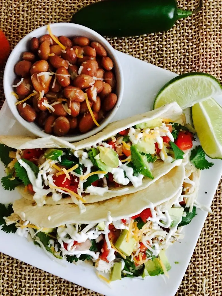 Crockpot Chicken Tacos on a Plate with a Bowl of Beans