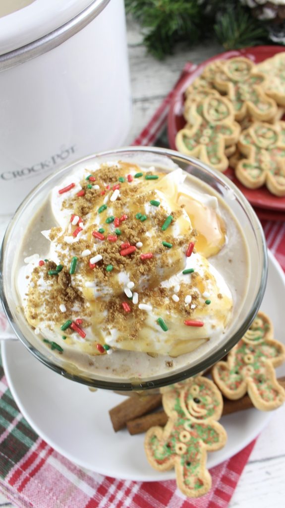 Crockpot Christmas Latte  Slow Cooker Fall Latte Recipe Glass with Latte Overflowing on a Plate with Crockpot in Background and a Plate of Cookies