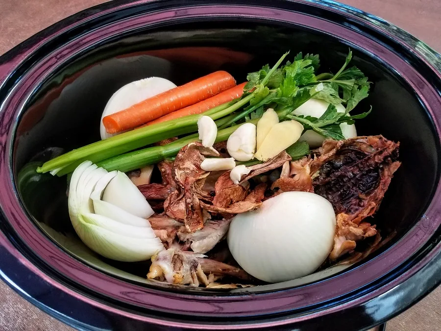 Slow Cooker Chicken Bone Broth Recipe Overhead View of Crockpot With Ingredients Inside