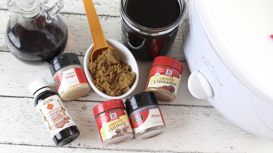 Festive Christmas Latte Recipe Seasonings for Latte Next to a Crockpot on a Wooden Surface