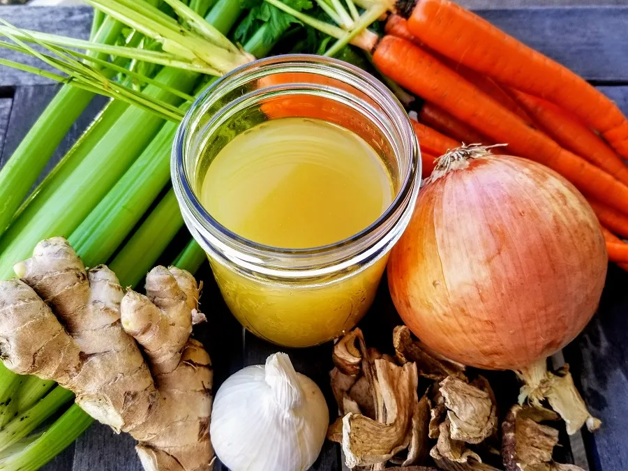 Slow Cooker Chicken Bone Broth Recipe Overhead View of Bone Broth in a Jar Surrounded by Ingredients