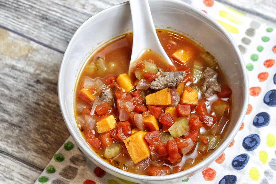 Healthy Instant Pot Vegetable Beef Soup Overhead View of Soup in a White Bowl with a White Spoon