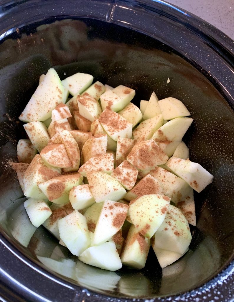 Crockpot Apple Crisp Apples in a Crockpot Covered in Cinnamon