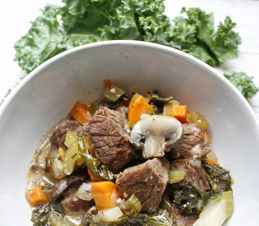 Healthy Slow Cooker Beef Stew Overhead View of a Bowl of Stew with Greens Next to It