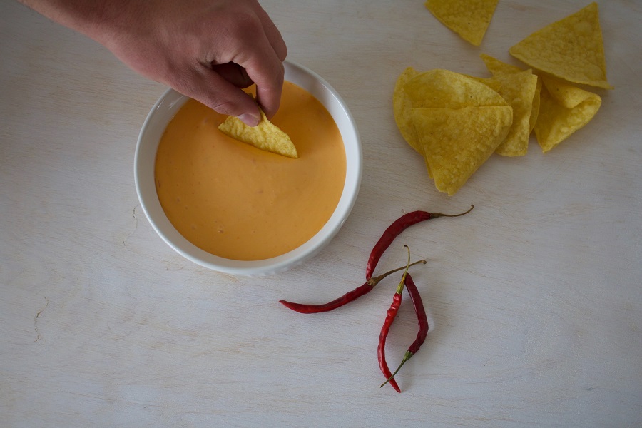 Crockpot Cheese Dip Recipes Person Dipping a Chip into Dip with Chips and Chiles Next to it