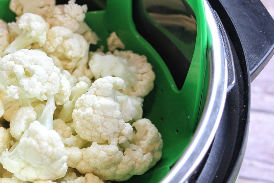 Instant Pot Cauliflower Mash Recipe Close Up of Cauliflower Florets in an Instant Pot with a Green Steamer Basket