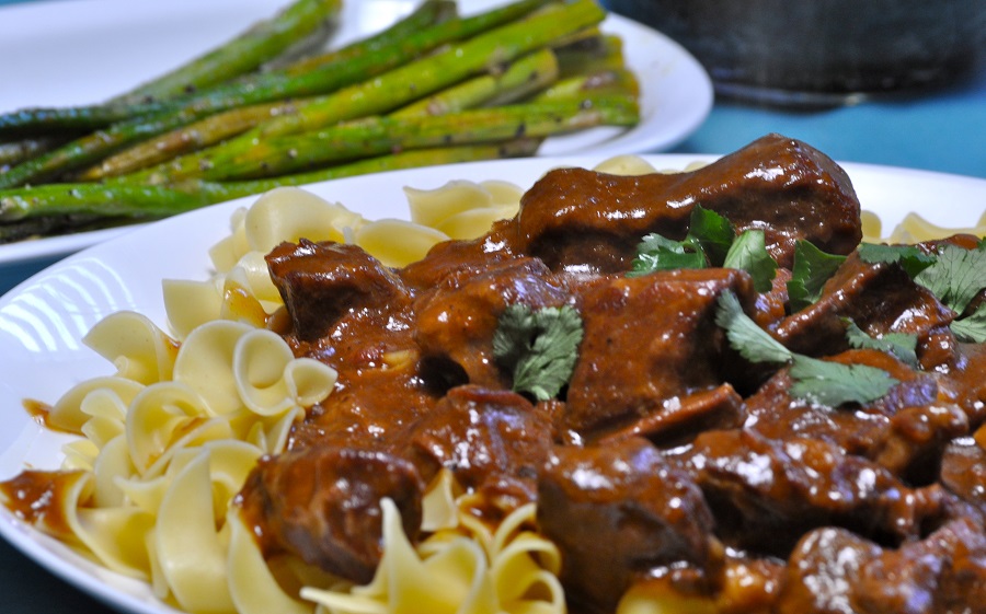 Budget Friendly Beef Stroganoff Close Up of Stroganoff on a Plate with Asparagus in the Background