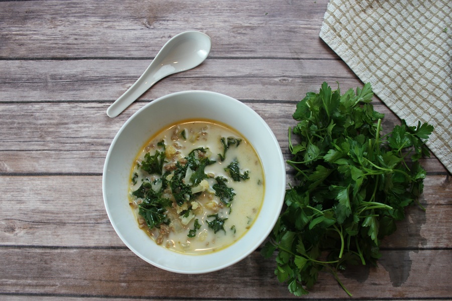 Easy Creamy Kale Soup Overhead View of a Bowl of Kale Soup with a Soup Spoon and a bundle of Parsley