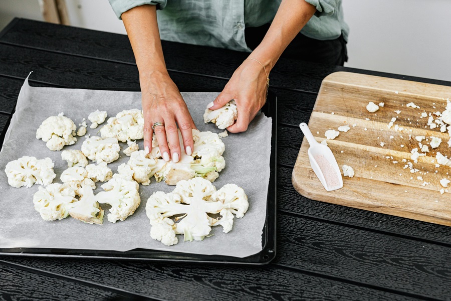 Instant Pot Recipes with Cauliflower Close Up of a Person Cutting Up Cauliflower and Placing it on Parchment Paper