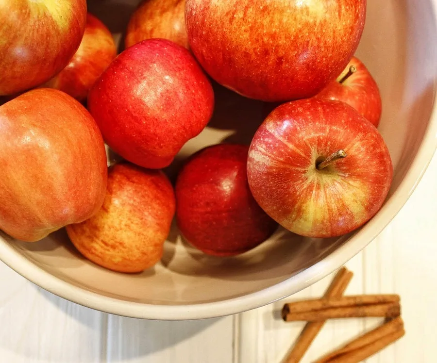 Instant Pot Cinnamon Apples Overhead View of Raw Apples in a Bowl with Cinnamon Sticks Next to it
