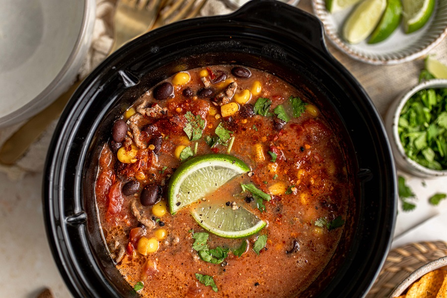 Crockpot Taco Soup Recipe Close Up of an Open Crockpot Filled with Taco Soup and Garnished with Two Lime Wedges