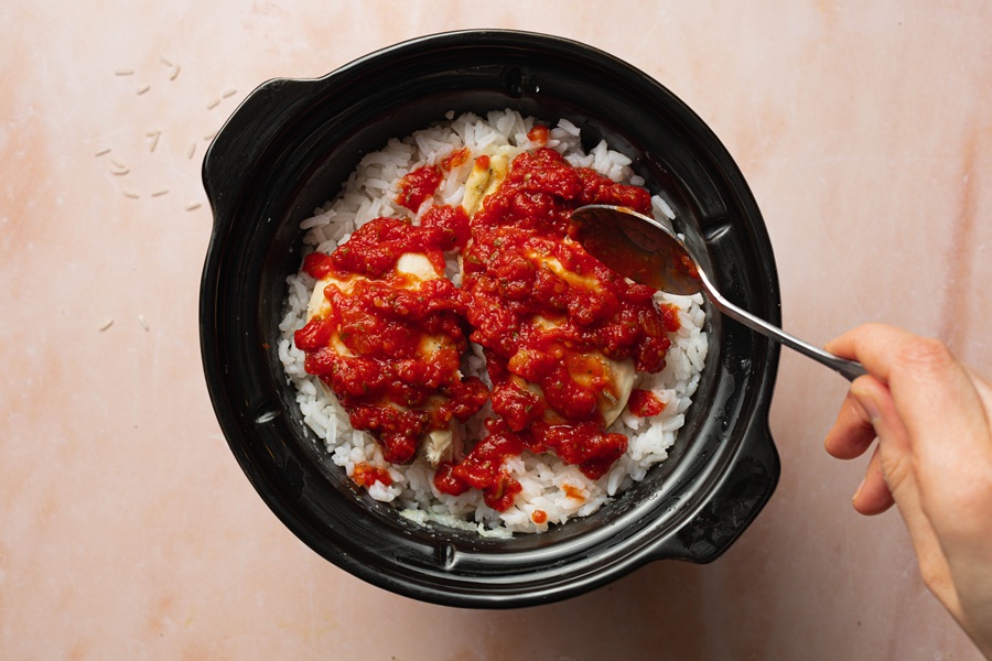 Salsa Chicken and Rice Crock Pot Recipe a Hand Spooning Salsa Into a Crock Pot with Chicken and Rice