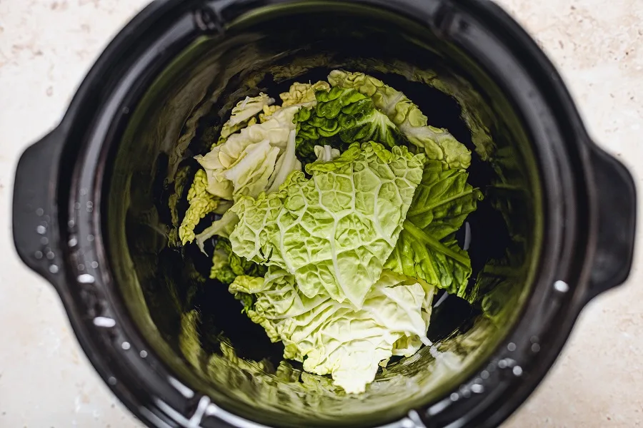 Unstuffed Cabbage Rolls Slow Cooker Recipe Inside View of a Crockpot with a Layer of Cabbage on the Bottom