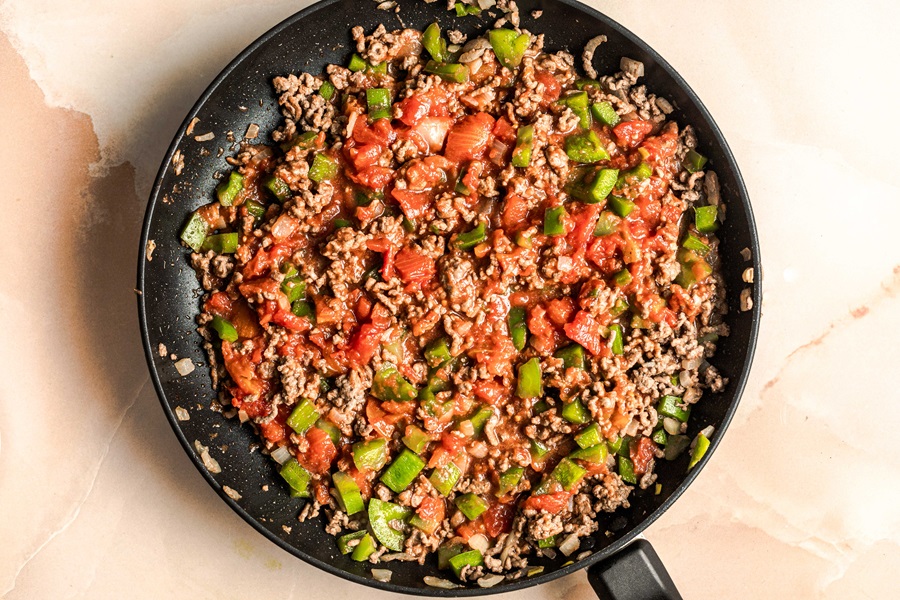 John Wayne Casserole with Tater Tots Recipes a Pan with Ground Beef Cooking Topped with Green Chiles and Tomatoes