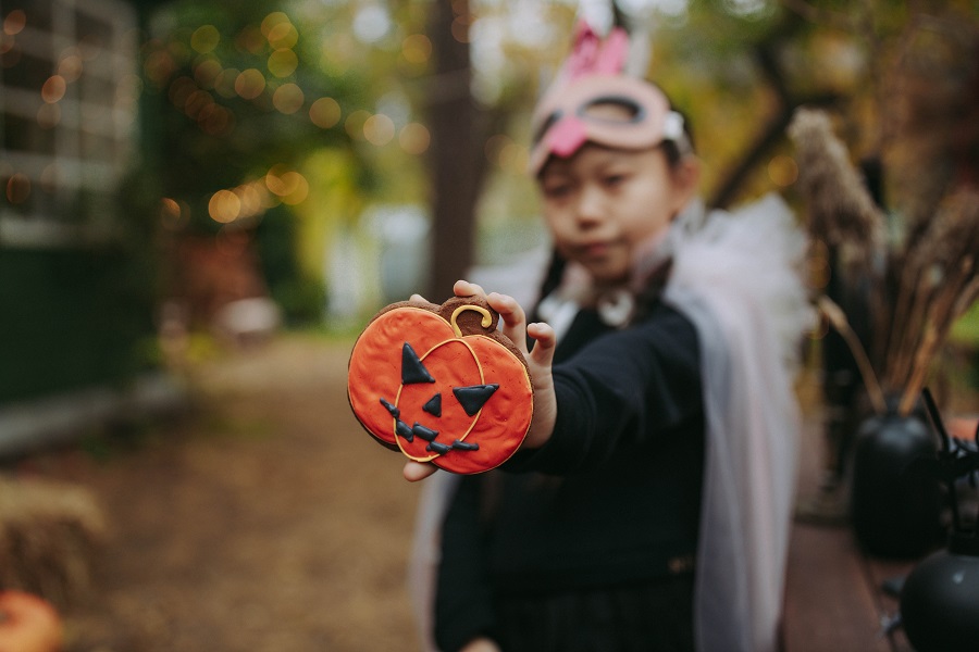 Instant Pot Halloween Recipes Kid in a Costume Holding Up a Jack-O-Lantern Cookie