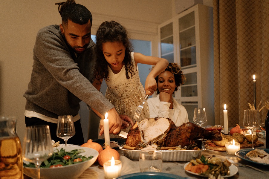 Crockpot Thanksgiving Recipes Family at the Dinner Table with Father and Daughter Cutting Turkey