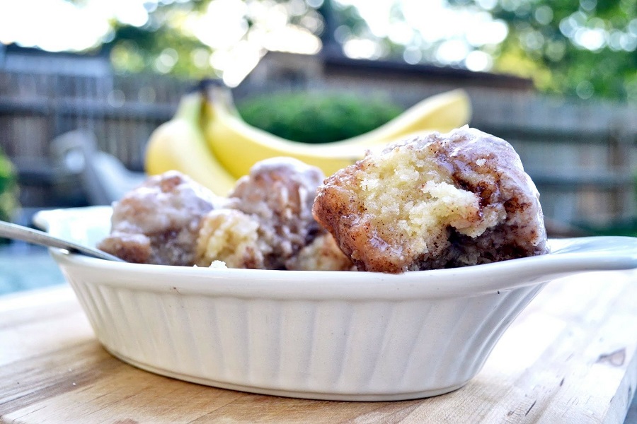 Crockpot Monkey Bread Recipes With Canned Cinnamon Rolls Close Up of a Bowl of Monkey Bread with Bananas in the Background on a Table Outside