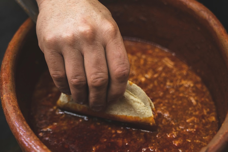 Crockpot Mexican Soup Recipes a Person's Hand Reaching into a Bowl of Soup with a Tortilla in Their Hand