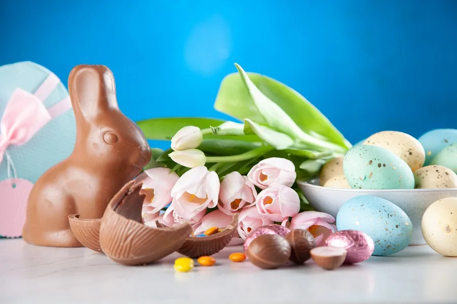 Easy Crockpot Easter Recipes Close Up of a Chocolate Easter Egg Broken Open with Eggs and Flowers in the Background
