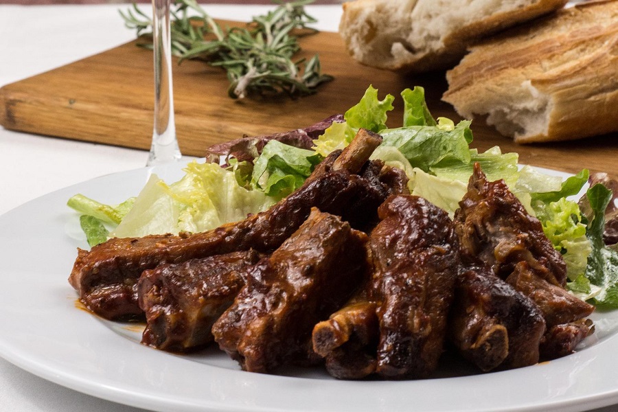 Slow Cooker Short Ribs Recipes Close Up of a Plate of Ribs with a Salad Behind Them