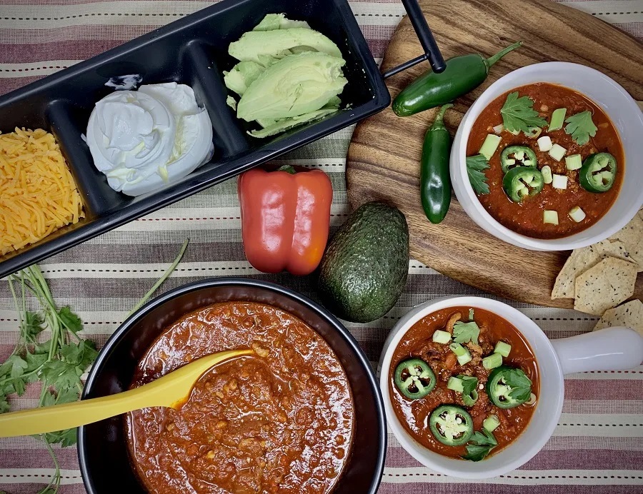 Instant Pot Beginner Recipes Overhead View of a Table with Two Bowls of Chili and an Array of Toppings