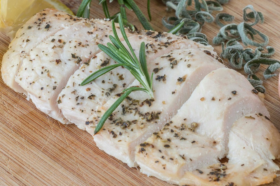 Best Slow Cooker Recipes with Chicken Close Up of a Cooked and Sliced Chicken Breast Topped with Herbs