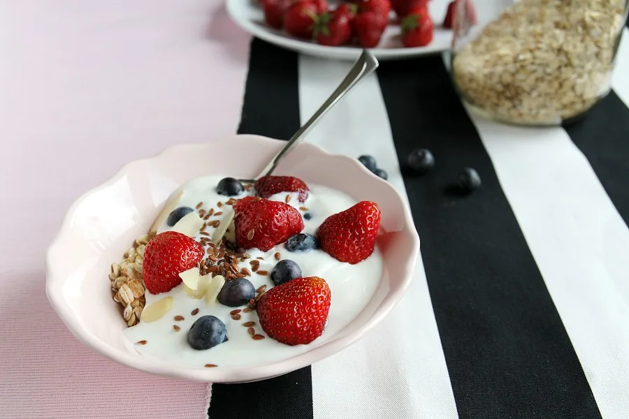 How to Make Instant Pot Yogurt a Bowl of Yogurt Topped with Strawberries on a Black and White Striped Table
