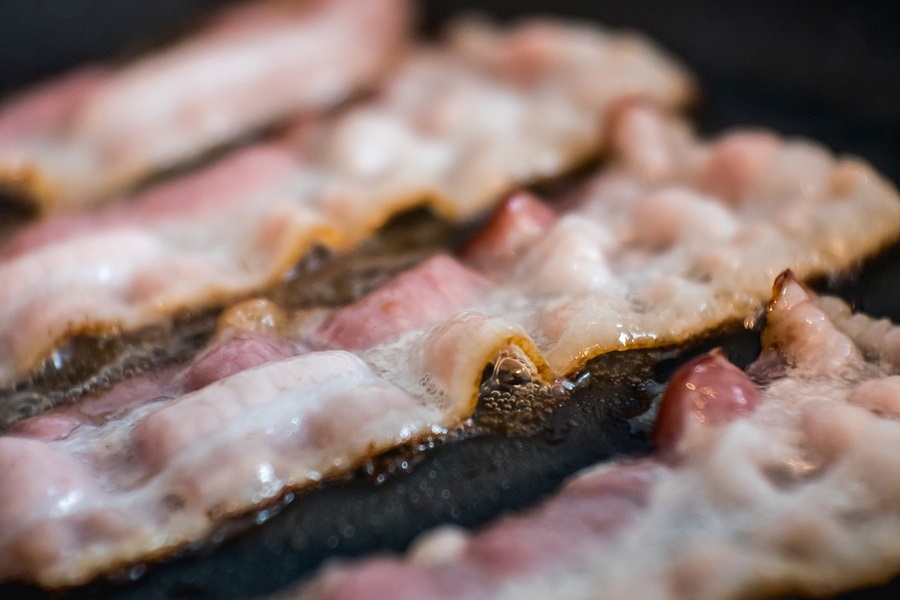 Best Slow Cooker Breakfast Recipes Close Up of 4 Strips of Bacon Frying in a Pan