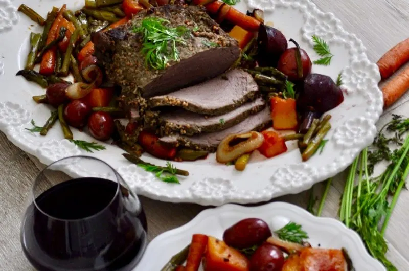 Dump and Go Crockpot Recipes a Pot Roast Sliced on a Platter with a Glass of Wine and Roasted Veggies