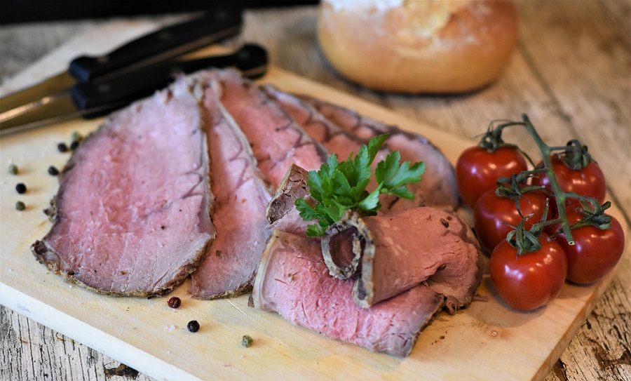 How to Make Instant Pot Beef Roast Sliced Roast Beef on a Cutting Board with Tomatoes and a Knife in the Background