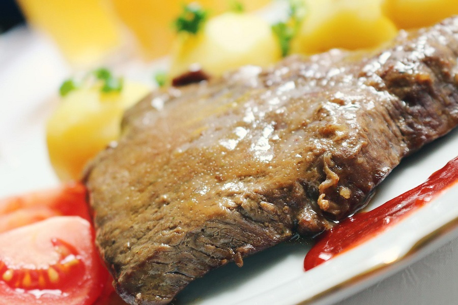 How to Make Instant Pot Beef Roast Close Up of a Slice of Roast beef on a Plate with Potatoes and Tomatoes