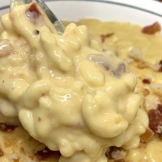 Kid Friendly Dump and Go Crockpot Recipes Close Up of a Spoon filled with Mac and Cheese Above a Plate of Mac and Cheese with Bacon Bits