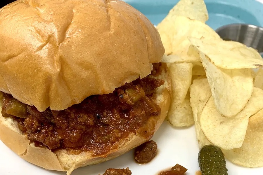 Kid Friendly Dump and Go Crockpot Recipes Close Up of a Sloppy Joe on a Plate with Chips and Pickles