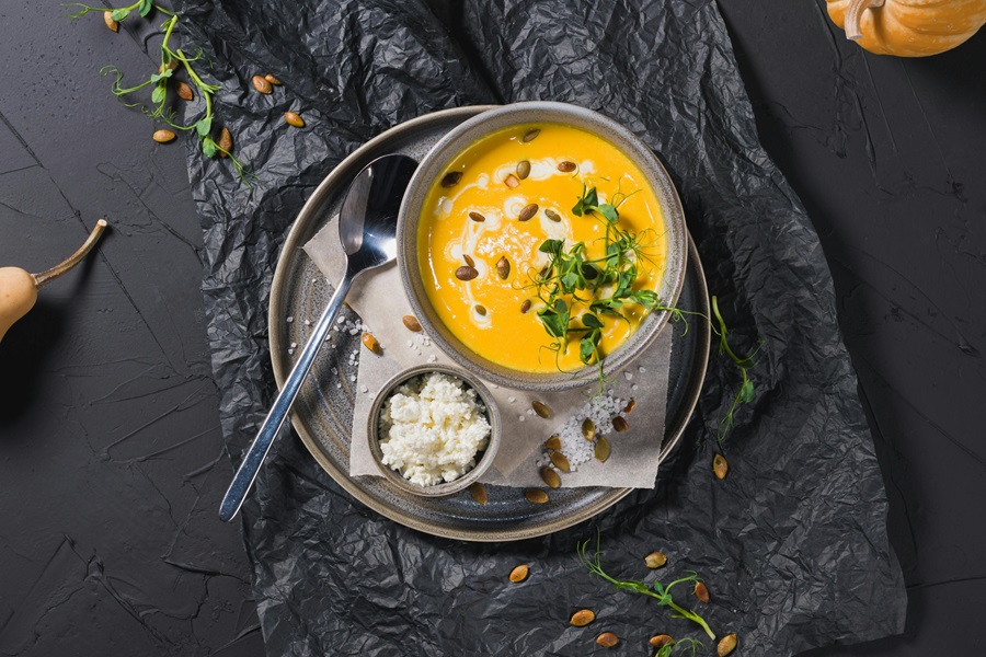 Cozy Fall Crockpot Recipes a Bowl of Pumpkin Soup with a Spoon on a Black Table