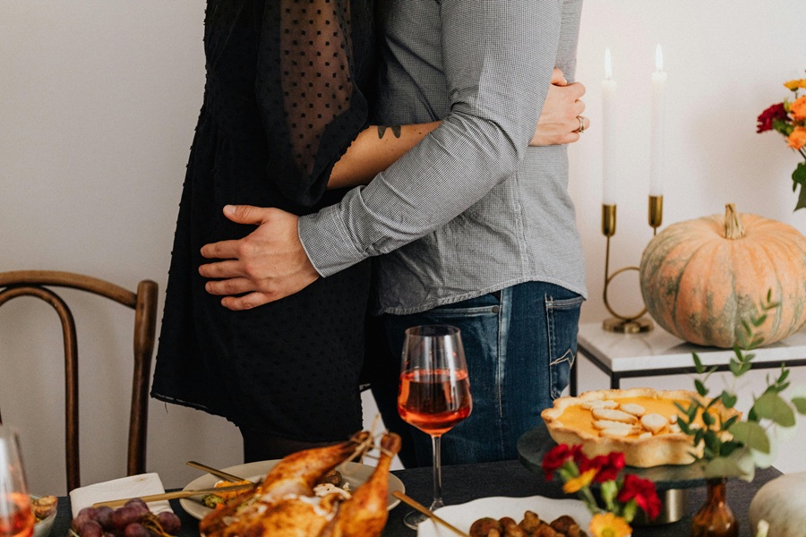 Best Crockpot Thanksgiving Desserts Two People Embracing Next to a Table with Thanksgiving Dinner Set