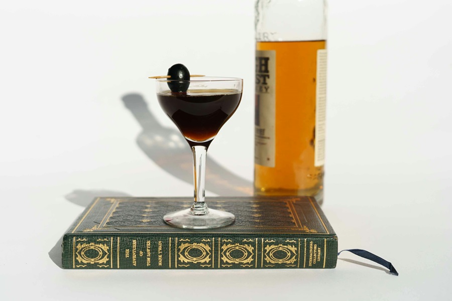 Crockpot Bourbon Punch Recipes a Cocktail on a Book with a Bottle of Bourbon in the Background