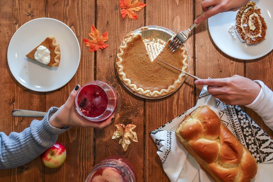 Easy Instant Pot Thanksgiving Appetizers Overhead View of a Dinner Table with Pumpkin Pie and Bread People's Arms Reaching for the Food