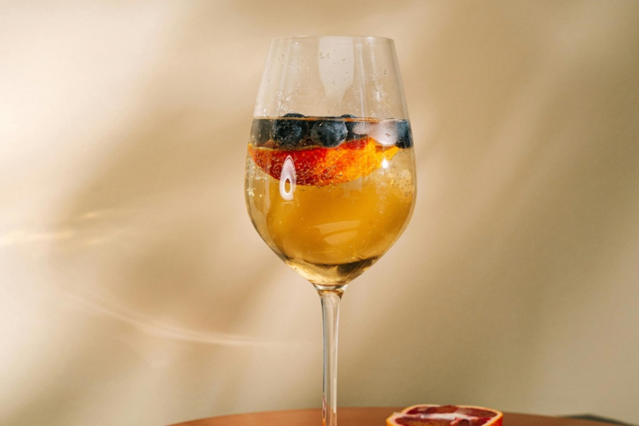 Sangria Recipes for Fall Close Up of a Glass of White Wine with Blueberries and Strawberries Floating Inside
