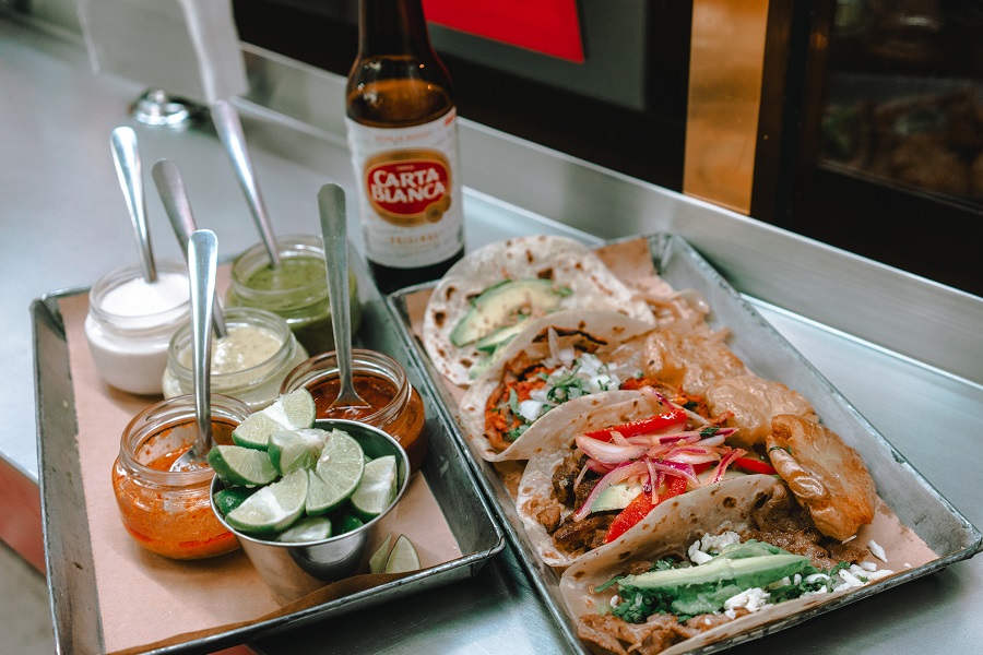 Instant Pot Frozen Chicken Recipes Simple Chicken Tacos on a Platter with Toppings Nearby and a Beer Bottle in the Background