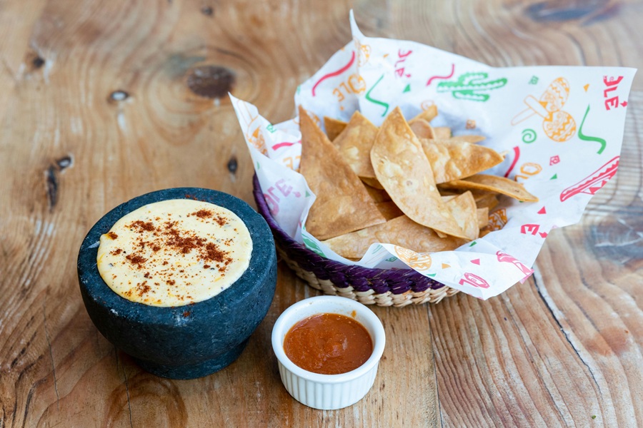 Super Bowl Appetizers a Small Basket of Tortilla Chips, a Bowl of Cheese Dip, and a Small Ramekin of Salsa on a Wooden Table