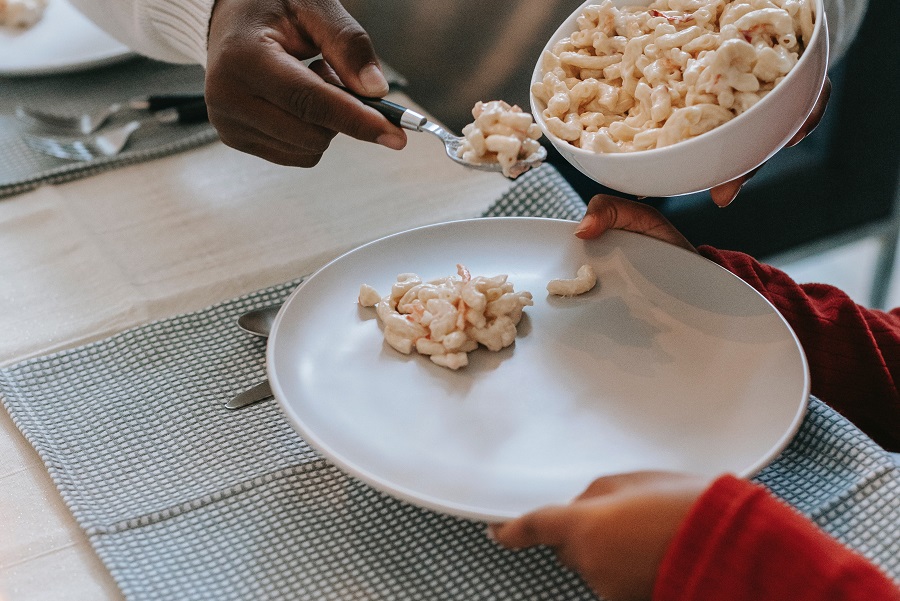 Instant Pot Mac and Cheese Recipes Close Up of a Person Scooping Mac and Cheese onto a Plate That is Held by a Child