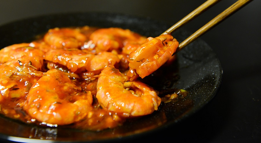 Can you Put Frozen Shrimp in Slow Cooker Close Up of a Person Picking Up Shrimp with Chopsticks from a Plate of Shrimp