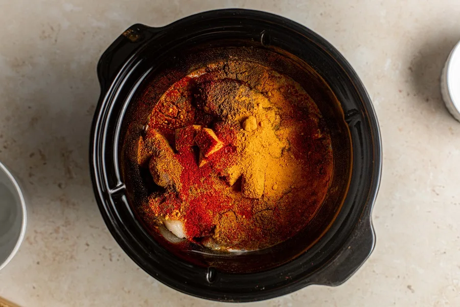Crockpot Chicken Tikka Masala Recipe View of the Inside of a Crockpot Filled with Ingredients and Covered in Seasonings