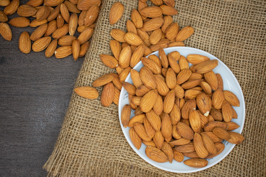 High Protein Grocery List  Overhead View of a Plate of Almonds with Almonds Spilling Off onto a Brown Cloth