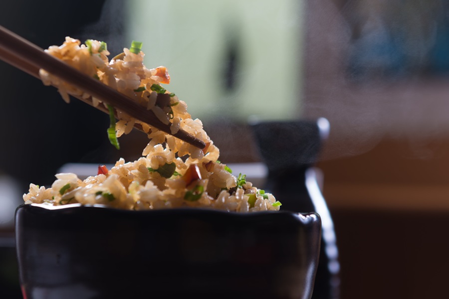 Instant Pot Rice Recipes from Around the World Close Up of a Small Bowl of Rice with Chopsticks Above It Holding Rice