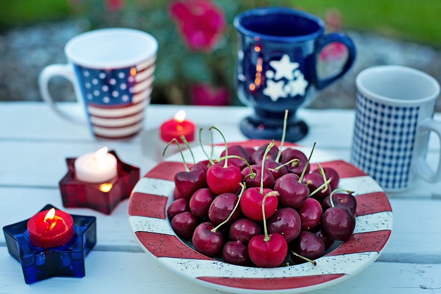 Patriotic Puns Close Up of a Plate of Cherries Surrounded by Patriotic Decor and Coffee Mugs