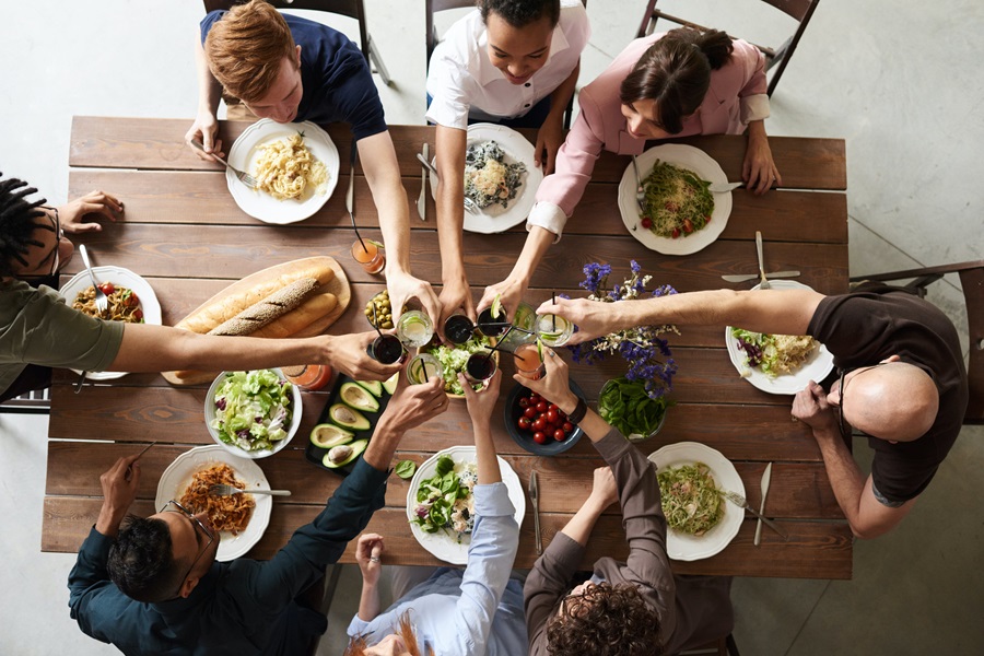 Best Crockpot Thanksgiving Sides Overhead View of a Table Filled with Food and People Sitting Around It Making a Toast