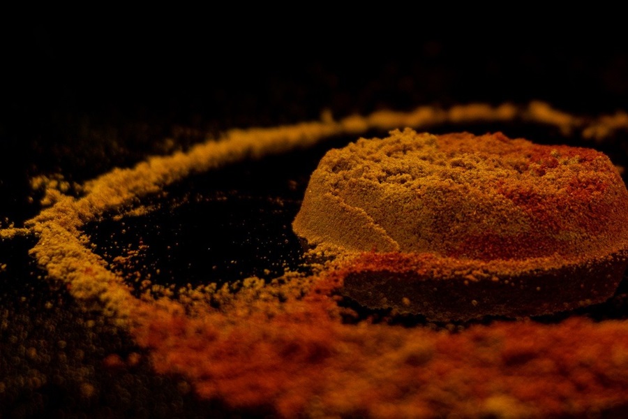 Chili Powder vs Cayenne a Small Pile of Cayenne Powder and Chili Powder on a Black Surface