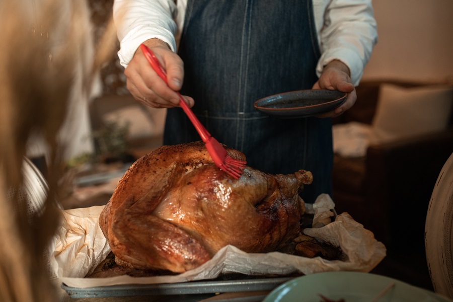 How to Smoke a Turkey in a Propane Smoker a Person Brushing Butter onto a Cooked Turkey with a Food Brush