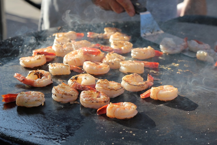 Texas Roadhouse Shrimp Recipe Ideas Close Up of Shrimp on a Grill with a Person Holding a Spatula in the Background